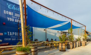 Outdoor patio with a blue tarp hanging over the benches and tables